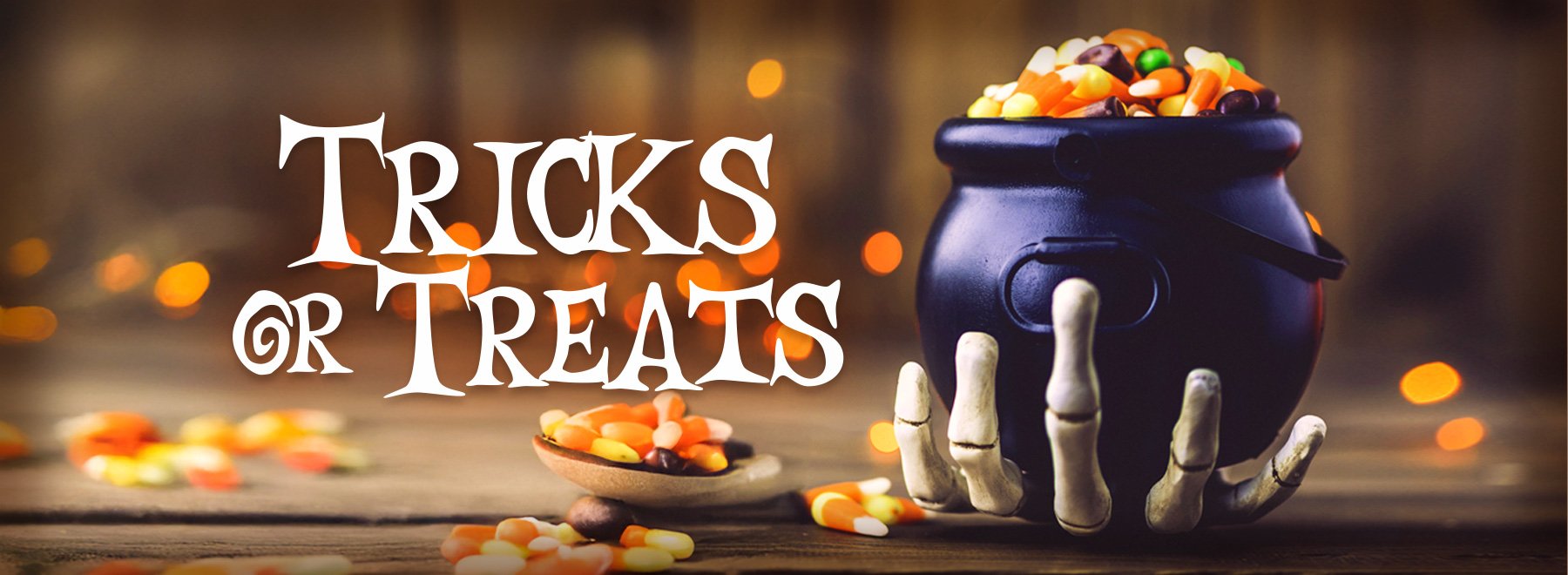 A Halloween-themed pot overflowing with candy, featuring a skeletal hand holding it.